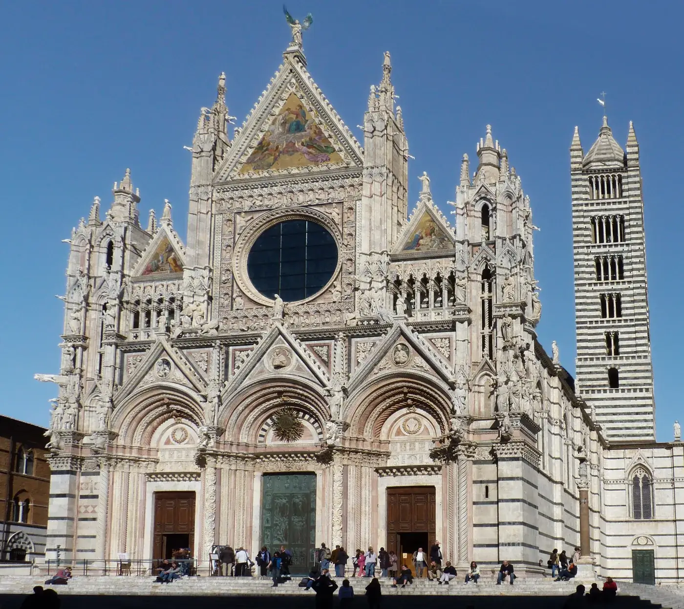 Black and white marble façade of Siena Cathedral under a blue sky