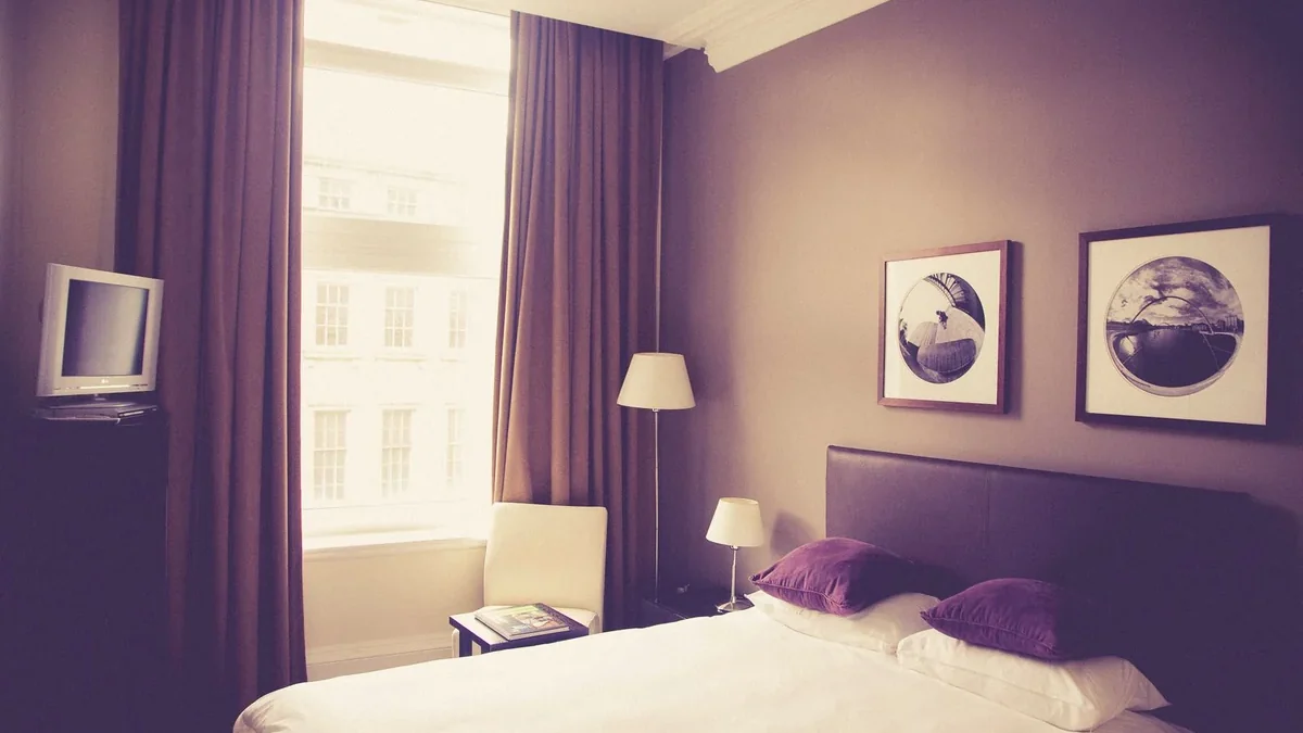 White bed linen beside a table lamp in a naturally lit room