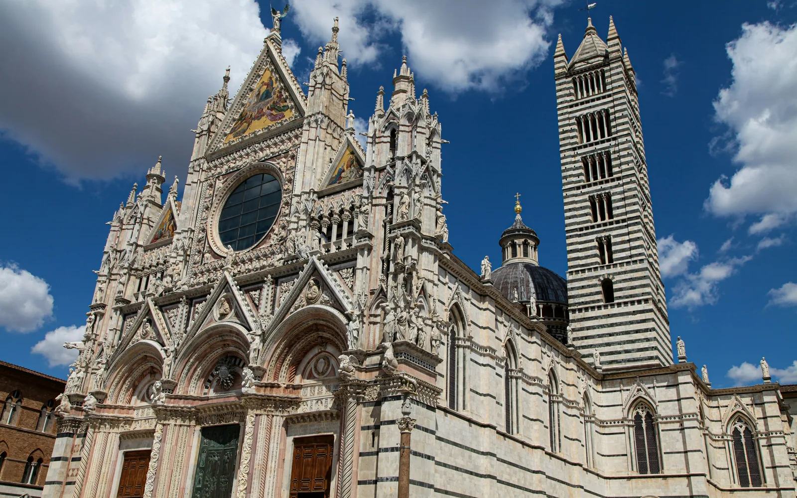 Ornate marble facade and towers of Siena Cathedral in Piazza del Duomo