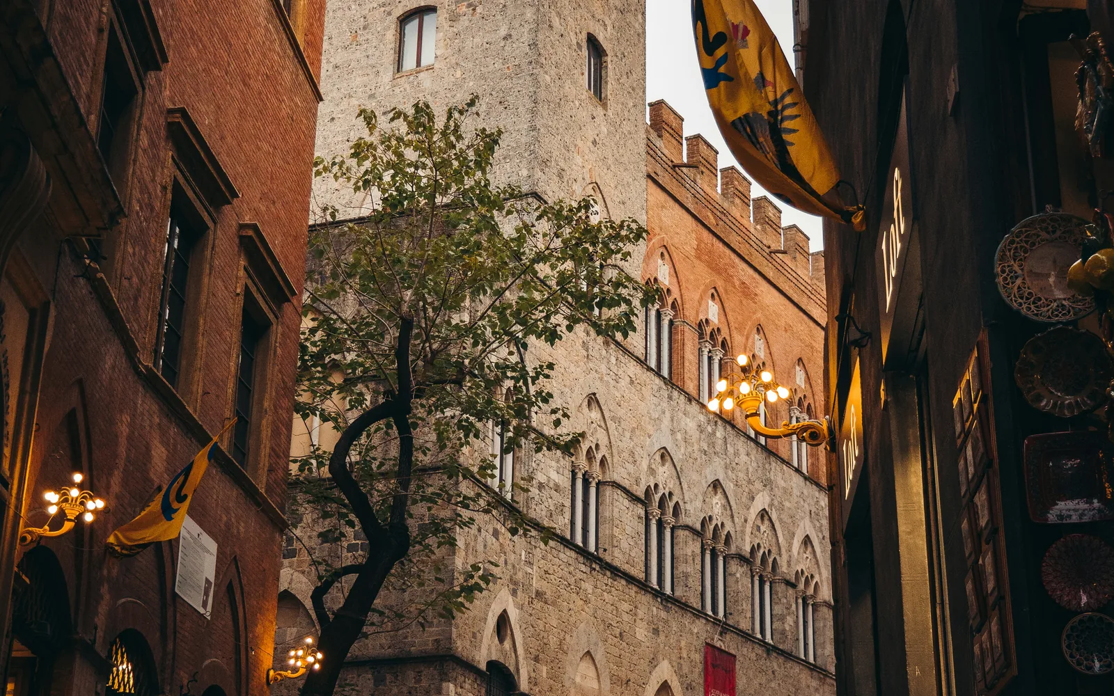 People walking through a narrow medieval street in Siena's historic centre